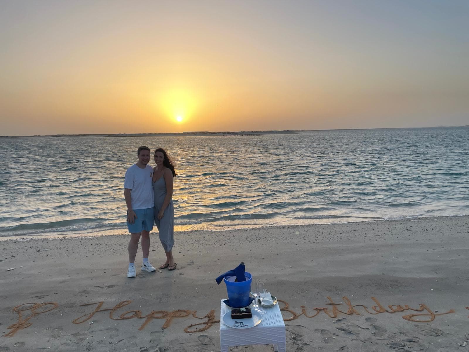 Sunset beach with Happy Birthday written in the sand