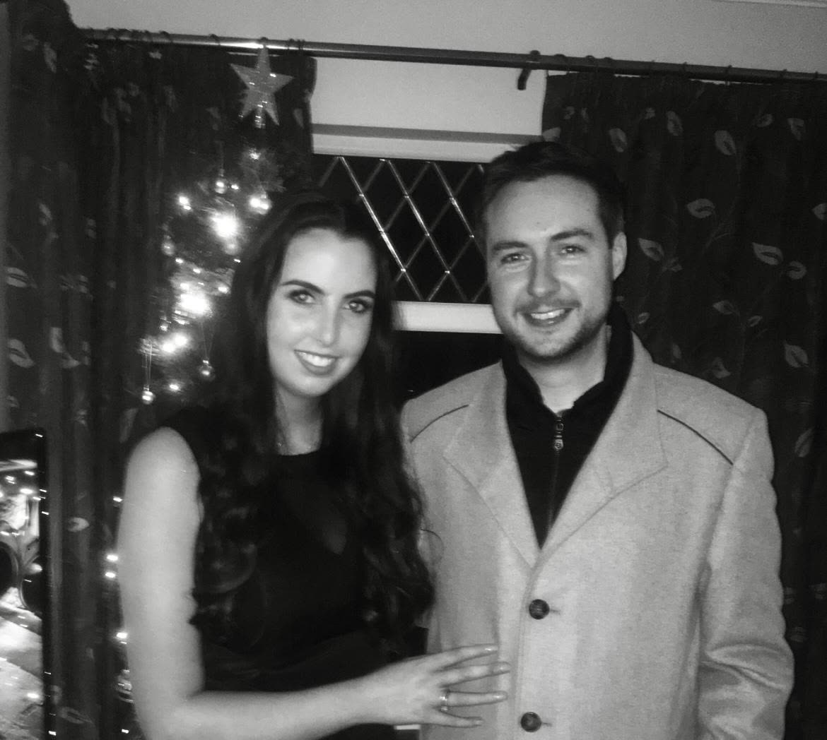 Black and white photo by the Christmas tree, ring hand showing