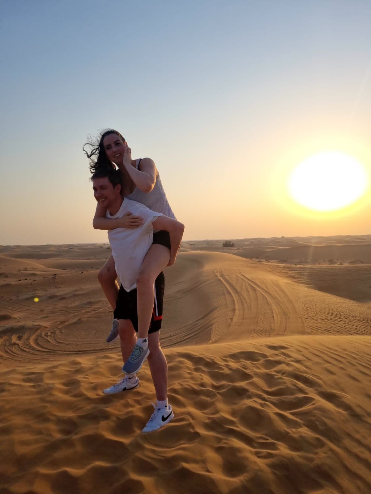 Piggyback on a desert dune at sunset in Dubai