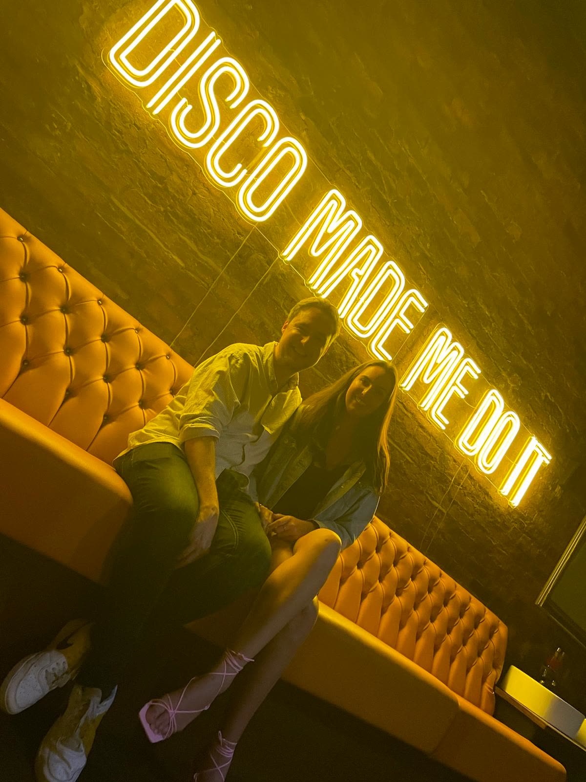 Under a neon sign that reads Disco Made Me Do It