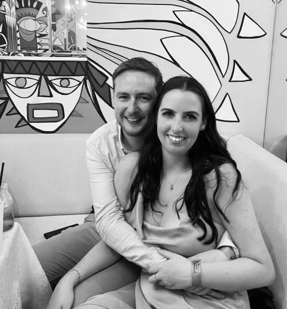 A black and white photo of the couple in front of a bold mural