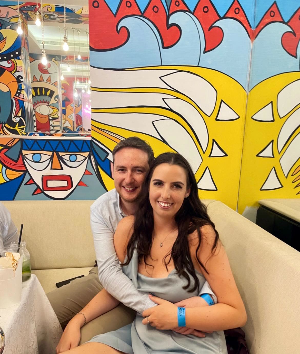 Cuddled in a booth in front of a bright mural